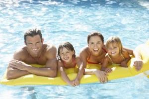 Young family, parents with children, in pool